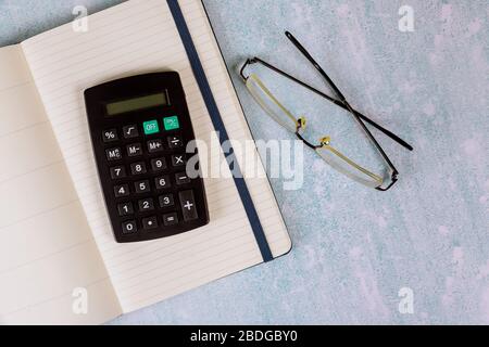 Büroschreibtisch mit Brillen auf offenem Notebook und Taschenrechner Stockfoto