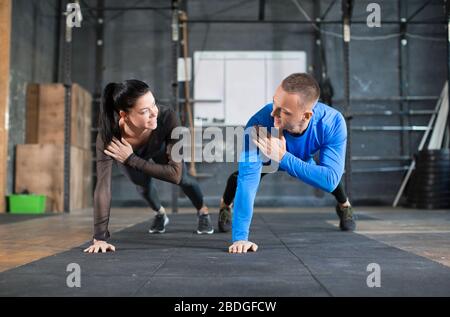 Mann und Frau Liegestütze beim Training im Fitnessstudio. Sport, Fitness und gesundes Lifestyle-Konzept. Stockfoto