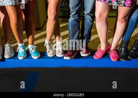 Junge Erwachsene Beine und Füße stehen zusammen auf einer blauen Kerb Stockfoto