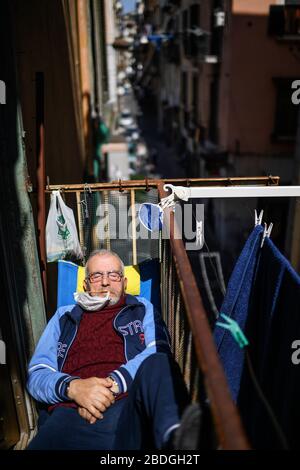 Neapel, Italien. April 2020. Ein Mann ruht in der Sonne auf einem Balkon mit Schutzmaske im spanischen Viertel (Quartieri Spagnoli) in der Innenstadt. In Italien wird der Sperrverfall weiterhin durch Regierungsdekret erklärt, das ganz Italien zu einem Schutzgebiet zur Bekämpfung der Kovidinfektion 19 erklärt - Coronavirus-Infektion, Schließung von Schulen, öffentlichen Büros und Geschäften. Kredit: Unabhängige Foto-Agentur Srl/Alamy Live News Stockfoto