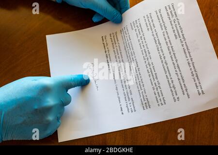 Mann, der chirurgische Handschuhe trägt, die den Brief der HM-Regierung mit der Unterschrift von Boris Johnson über Covid-19 Coronavirus, Großbritannien, enthalten Stockfoto