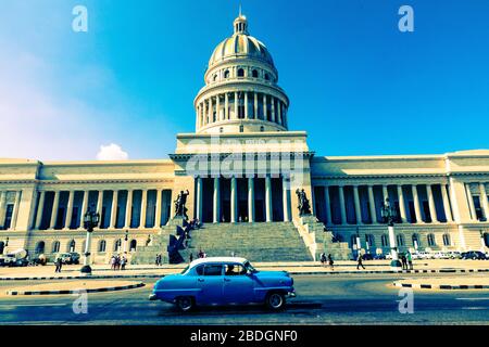 HAVANNA, KUBA - 10. DEZEMBER 2019: Farbige klassische amerikanische Autos, die als Taxis dienen, fahren auf der Hauptstraße vor dem Kapitolio-Gebäude i vorbei Stockfoto