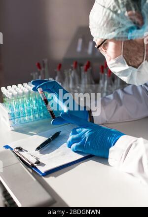 Hände eines Arztes in einem Labor. Machen Sie sich Notizen bei der Erforschung von Anti-Virus-Impfstoff. Ansicht von oben. Stockfoto