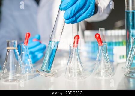 Ein Arzt in einem Labor arbeitet an einem Impfstoff gegen das Virus. Nahsicht eines Arztes, der eine Flasche auf einen Tisch legt. Stockfoto
