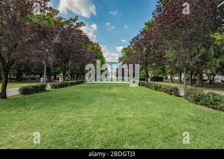 Como, ITALIEN - 4. August 2019: Lokale Menschen und Touristen auf der Viale Guglielmo Marconi in der Nähe des Comer Sees. Tempio Voltiano Museum im Hintergrund. Warme sonne Stockfoto