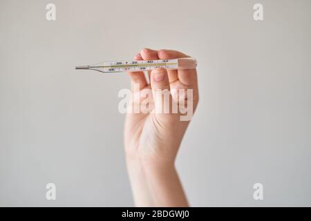 Mädchen hält ein Thermometer. Hohe Körpertemperatur auf einem Thermometer. Stockfoto