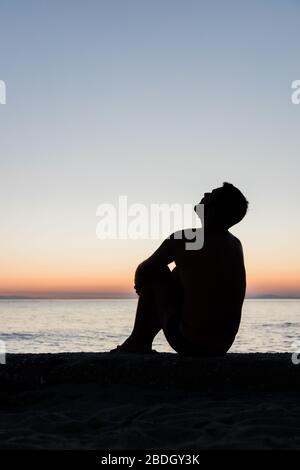 Silhouette eines Mannes am Meer bei Sonnenuntergang Stockfoto
