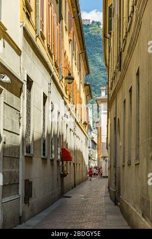 Como, ITALIEN - 4. August 2019: Lokale Menschen und Touristen in einer ruhigen, gemütlichen Straße im Zentrum der schönen italienischen Comer Stadt. Warm sonniger Sommertag in Stockfoto