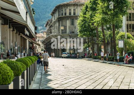 Como, ITALIEN - 4. August 2019: Lokale Menschen und Touristen in einer ruhigen, gemütlichen Straße im Zentrum der schönen italienischen Comer Stadt. Warm sonniger Sommertag in Stockfoto