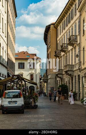 Como, ITALIEN - 4. August 2019: Lokale Menschen und Touristen in einer ruhigen, gemütlichen Straße im Zentrum der schönen italienischen Comer Stadt. Warm sonniger Sommertag in Stockfoto