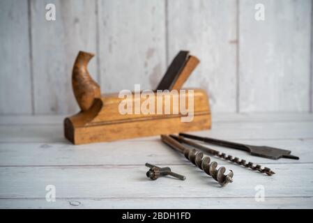 Vintage-Werkzeuge. Vintage Bohrer mit Vintage Holzhobel vor weißem Holzhintergrund Stockfoto