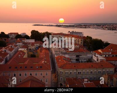 Luftlinie Blick auf Zadar, Kroatien während Sonnenuntergang mit schönen roten Himmel und großen runden Sonnenuntergang an der Adria. Stockfoto