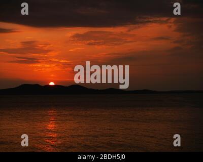 Schöner roter Sonnenuntergang über der Adria und den Bergen im Horizont und schöne Wolken, Zadar, Kroatien Stockfoto