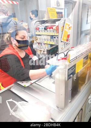 Ukraine, Kiew am 7,2020. März.Woman Kassierer in einer schwarzen medizinischen Maske akzeptiert die Zahlung für die Waren aus Billa Shop während der Quarantäne des Coronavirus Stockfoto