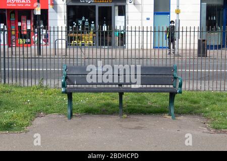 Eine leere Parkbank in der Nähe einer Hochstraße mit geschlossenen Geschäften während der Covid-19-Pandemie, London UK Stockfoto