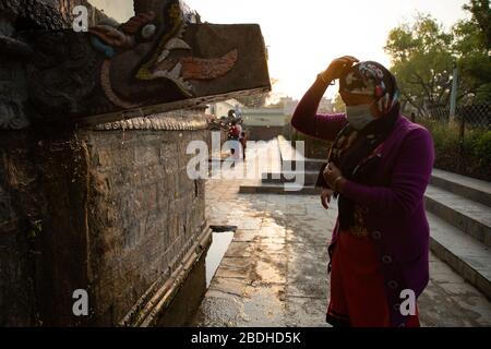 Kathmandu, Nepal. April 2020. Eine nepalesische hindu-frau, die eine Gesichtsmaske trägt, während sie während des Baisdhara Mela Full Moon Festivals in Kathmandu, Nepal am 08. April 2020 Wasser auf sich spritzelt. Tausende von Gläubigen versammeln sich, um in 22 Wasserspächten Balaju heiliges Bad zu nehmen, um ihre spirituelle Reinigung und im Glauben an viele Krankheitsbehandlungen zu erhalten. Aber dieses Jahr nahmen nur wenige Anhänger Teil, da Nepal landesweit im Kampf gegen die Ausbreitung der COVID-19-Pandemie steht. (Foto von Subash Shrestha/Pacific Press) Credit: Pacific Press Agency/Alamy Live News Stockfoto