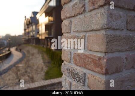 Alte Backsteinmauer und moderne Architekturgebäude im Hintergrund bei Sonnenuntergang Stockfoto