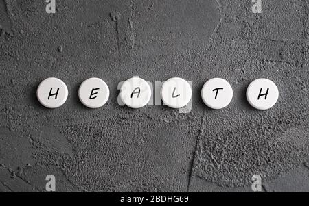 Gesundheitswort auf die Pillen auf grauem Hintergrund gedruckt. Meldung über den Systemzustand. Stockfoto