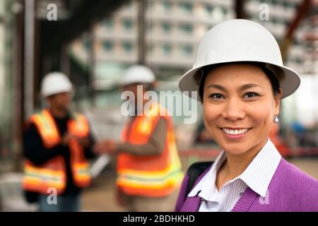 Porträt der lächelnden Architektin mittleren Alters, die eine Baustelle besucht. Stockfoto