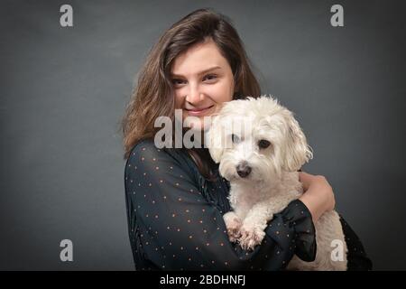 Teen Girl mit Maltese Dog in ihren Händen im Studio Stockfoto