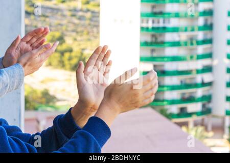 Die Familie lobt das medizinische Personal vom Balkon. Menschen klatschen auf Balkons und Fenstern, um die Gesundheit der Mitarbeiter während der Coronavirus Pandemie zu unterstützen Stockfoto