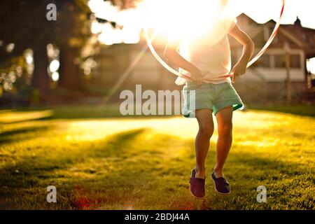 Junge Mädchen durch ein Hula Hoop springen. Stockfoto