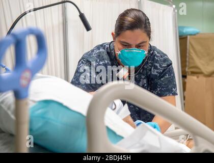 U.S. Navy Hospital Corpsman 1st Class Leslie Simmons, führt eine Bewertung eines Patienten zur Atempflege an Bord des Hospitalschiffs USNS Mercy durch, das zur Unterstützung der COVID-19, Coronavirus Pandemie eingesetzt wurde, die am 7. April 2020 in Los Angeles, Kalifornien angedockt wurde. Stockfoto