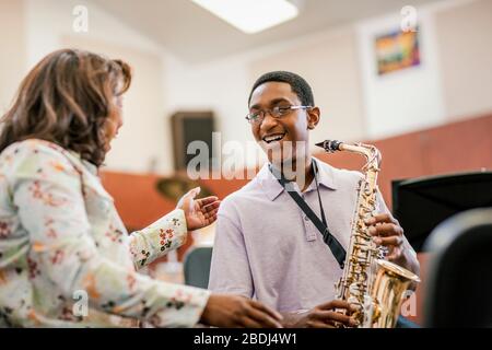 Fröhlicher Teenager mit seinem Musiklehrer in der Klasse Stockfoto