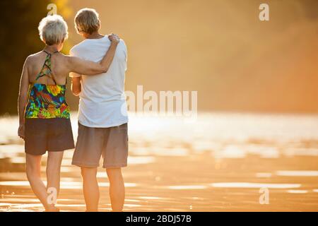 Glückliches älteres Paar, das nebeneinander an einem See steht Stockfoto