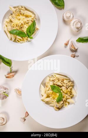 Klassische Penne Pasta in großen weißen Platten auf hellem Hintergrund. Traditionelle mediterrane Küche. Vertikaler Schuss Stockfoto