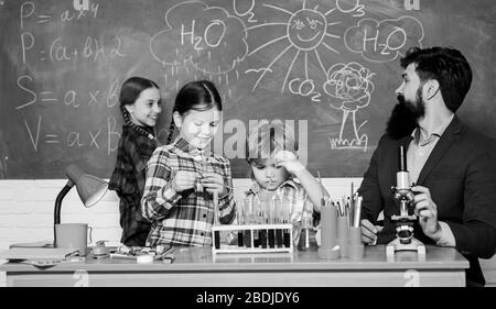 Wissenschaft ist immer die Lösung. Reaktion beobachten. Experiment der Schulchemie. Erklären der Chemie für Kinder. Faszinierende Chemiestunde. Mann bärtige Lehrer und Schüler mit Reagenzgläsern im Klassenzimmer. Stockfoto