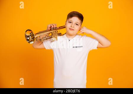 Ein gutaussehender Junge in einem weißen T-Shirt hält ein Pfeifeninstrument auf einem Herd. Der Junge mit der Pfeife zeigt eine Handgeste. Rufen Sie mich am Telefon an. Stockfoto