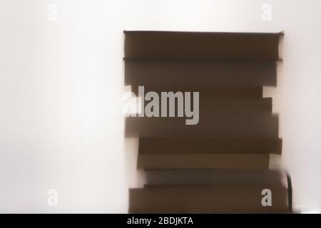 Ein Stapel Bücher übereinander. Durch ein halbtransparentes Material geschossen. Ein strukturiertes, verschwommenes, wunderschönes Stillleben. Stockfoto