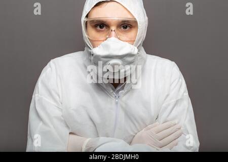 Coronavirus Kovid-19-Desinfektion. Portrait kaukasischer Arzt im medizinischen Schutzanzug, biologische Gefahr, medizinische Maske FFP3, Schutzbrille auf grau isoliert Stockfoto