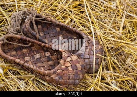 Bast Schuhe auf dem Stroh, traditionelle Weidenschuhe des alten Russland. Nahaufnahme Stockfoto