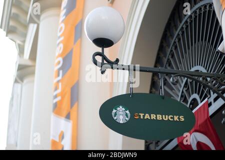 Starbucks Schild hängt oval. Weiße runde Straßenleuchte oben. Stockfoto