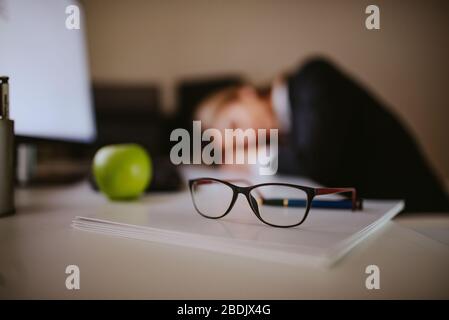 Müde junge blonde kaukasische Geschäftsfrau schläft im Büro Stockfoto