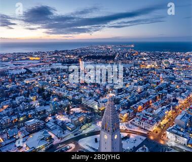 Luftbild des Hallgrimskirkja-Kirchturms über der beleuchteten Straße der Stadt in düsterer Zeit Stockfoto