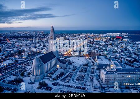 Luftbild der Hallgrimskirkja-Kirche im Zentrum von Reykjavik mit Nachtlicht beleuchtet und in der Dämmerung mit Schnee bedeckt Stockfoto