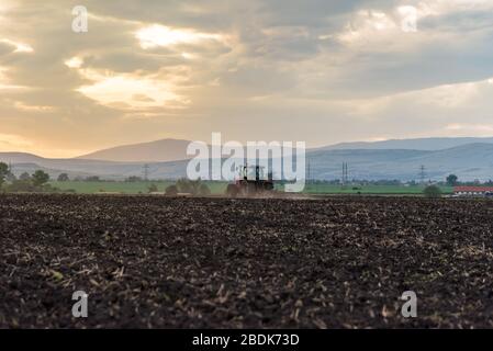 Landwirtschaftlichen Traktor Pflügen und Spritzen auf dem Feld. Stockfoto