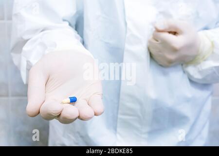 Blaue und weiße Pille in den Ärzten Hand mit Handschuhen. Konzept zur Heilung von Krankheiten, selektiver Fokus. Stockfoto