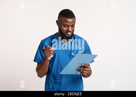 Afrikanischer Arzt, der das Formular überprüft und ausgefüllt hat Stockfoto