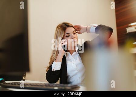 Junge attraktive Geschäftsfrau telefoniert im Büro Stockfoto