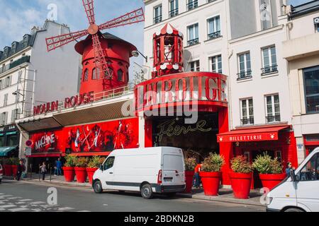Pariser Kabarett Moulin Rouge. Roter Turm, Mühlflügel und Aufschrift Moulin Rouge . In der Nähe - ein malerischer Turm mit einer Aufschrift von Bars Stockfoto