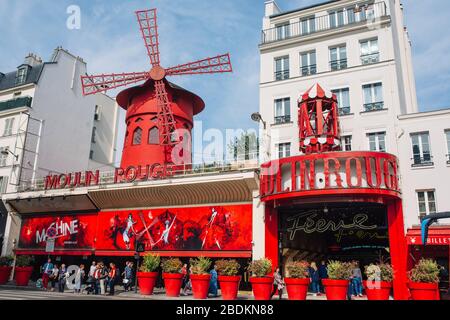 Pariser Kabarett Moulin Rouge. Roter Turm, Mühlflügel und Aufschrift Moulin Rouge . In der Nähe - ein malerischer Turm mit einer Aufschrift von Bars Stockfoto