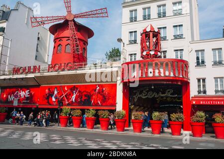 Pariser Kabarett Moulin Rouge. Roter Turm, Mühlflügel und Aufschrift Moulin Rouge . In der Nähe - ein malerischer Turm mit einer Aufschrift von Bars Stockfoto