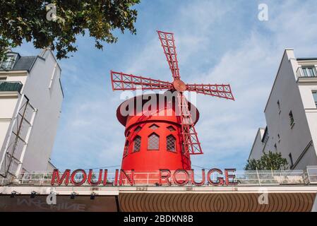 Pariser Kabarett Moulin Rouge. Roter Turm, Mühlflügel und Aufschrift Moulin Rouge . In der Nähe - ein malerischer Turm mit einer Aufschrift von Bars Stockfoto