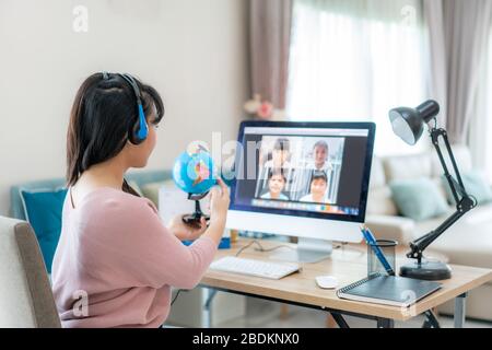 Asian Woman Teaching Geography per Videokonferenz E-Learning und fröhliche Grundschüler mit Blick auf Globe, Homeschooling und dist Stockfoto