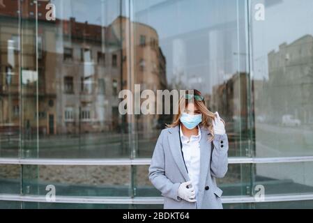 Nahaufnahme der jungen hübschen kaukasischen blonden Geschäftsfrau mit Maske vor der Firma. Stockfoto