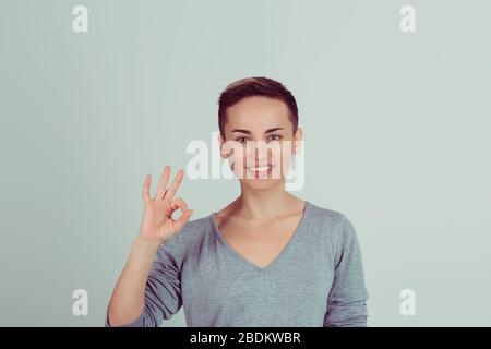 Schöne junge Frau mit OK-Schild isoliert auf grün-weißem Wandhintergrund. Positive menschliche Emotionen sind Ausdruck Körpersprache. Horizontale Studie Stockfoto